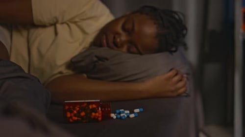Woman Sleeping with Medication on Bedside Table