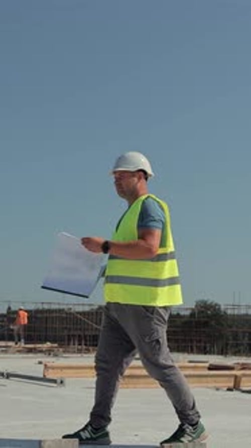 Architect Reviewing Blueprints at Modern Construction Site An Architect in a Reflective Vest and
