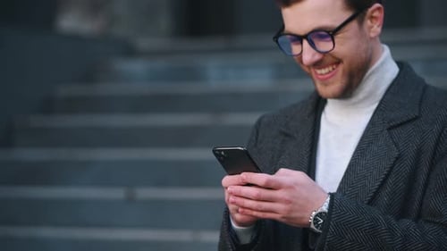 Man Smiles and Uses Smartphone in Urban Setting