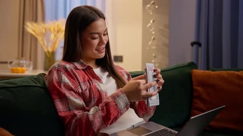 Young Woman Counts Money on Couch at Home