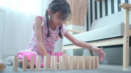A Little girl having fun playing dominoes in the living room of the house