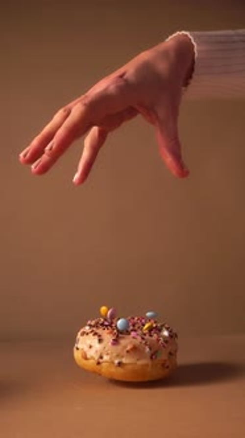 Slow Motion Donut Dropping from Hand with Colorful Sprinkles