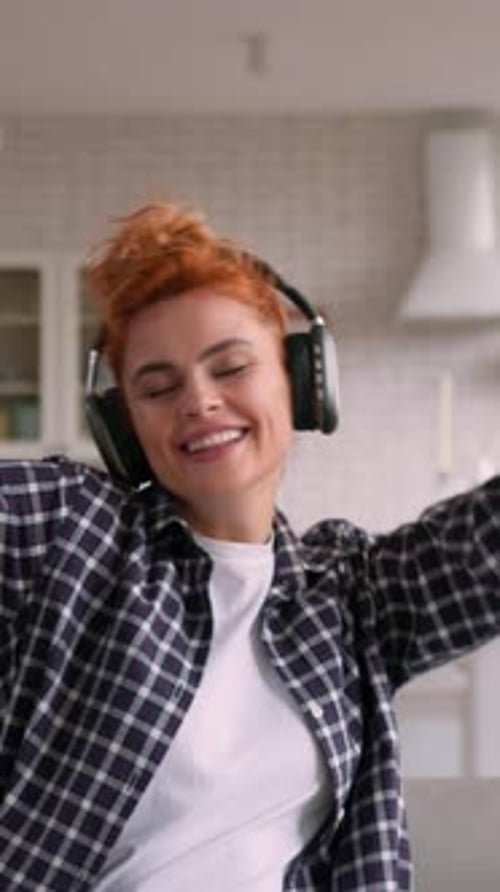 Woman Happily Listening to Music with Headphones Indoors