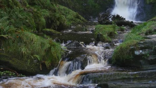 A lovely stream with flowing water over the rocks at the base of Pistyll Rhaeadr Falls, It's the hi