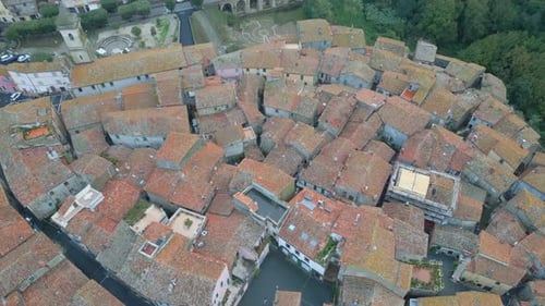 Drone flies over the rooftops of a medieval Italian town on a cloudy day