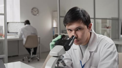 Young Man Looking Through Microscope in Lab