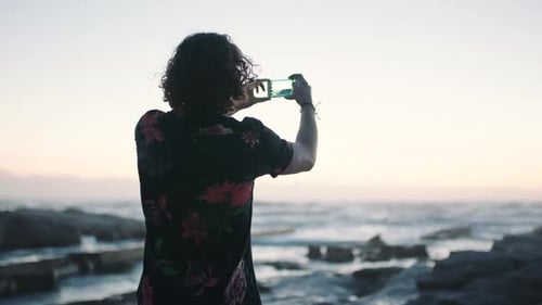 Beach, sunset and photography, man with phone taking holiday picture in Bali