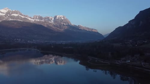 Aerial ascending view of Passy lake and the town of Sallanches early in the morning. First rays of s