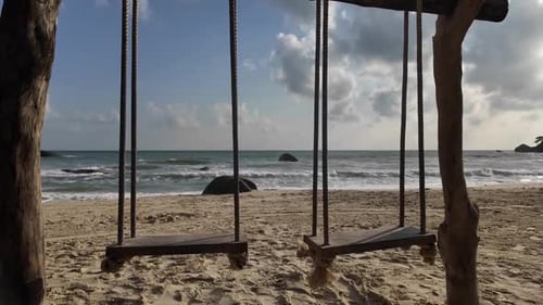 Ein paar verlassene Holzschaukeln an einem Sandstrand am Meer an einem sonnigen Tag. Ein Touristenziel