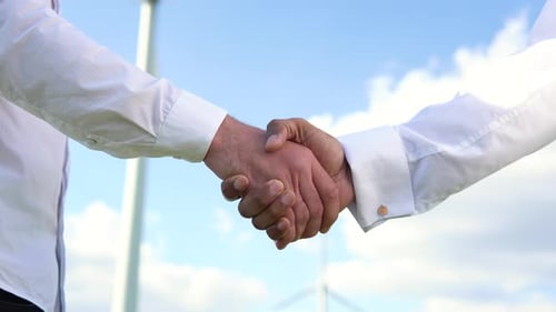 Close Up Two Multiracial Man Wind Turbine Engineers Working and Shaking Hands at Wind Turbine Farm