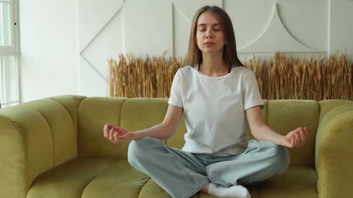 Woman Meditating Peacefully on Couch Indoors