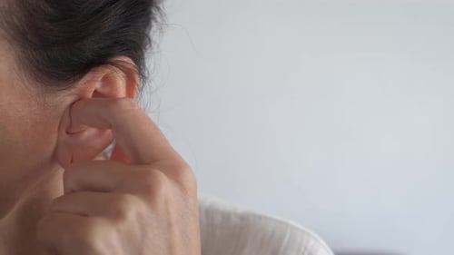 Adult Touches Ear Wearing Gold Hoop Earring
