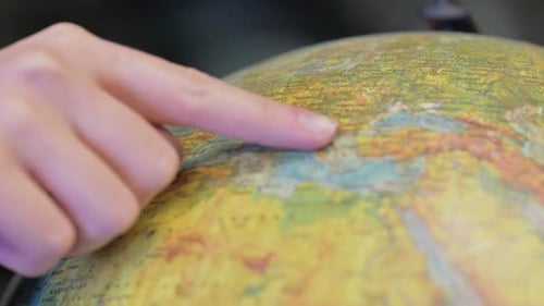 Primer plano de la búsqueda con el dedo de un hombre en Globe of World