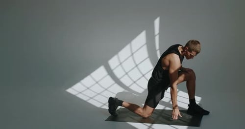 Athletic Young Man Doing Lunges in a Modern Studio Setting