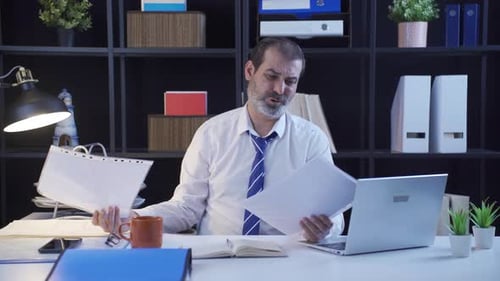 Office worker is reading paperwork and is upset.