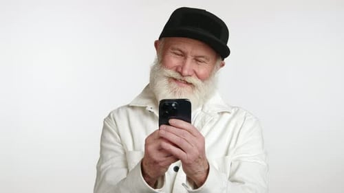 Senior Man Smiles Using Smartphone