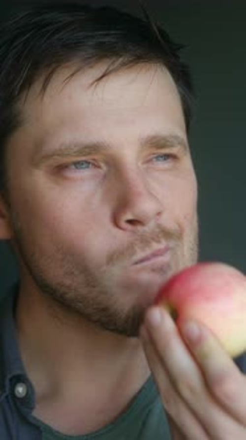Man takes large bites from a red apple