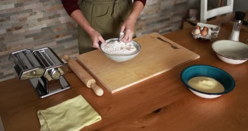 Woman Sprinkling Flour on a Wooden Board for Homemade Pasta