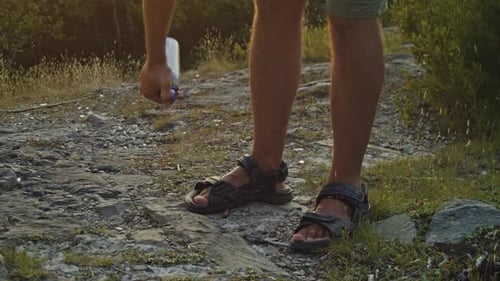 Man Sprays Mosquito Repellent at Sunset on Mountain