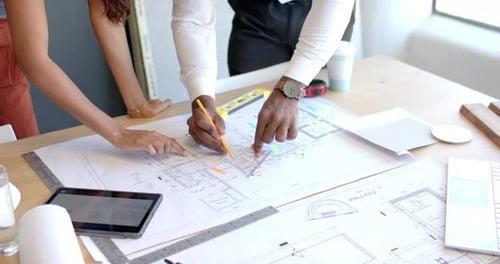 Architects Collaborating on Blueprint in Modern Office