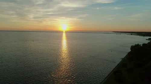 Beautiful sunset in the evening over a massive lake with a long bridge in the horizon.