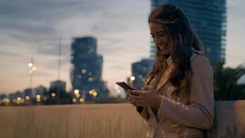 Young Beautiful Woman Entrepreneur laughing sending a voice mobile phone message on a city street