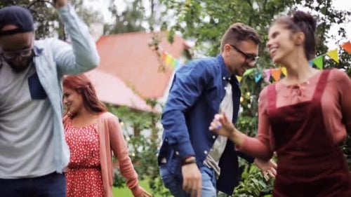 Happy friends dancing together at summer party in garden slow motion