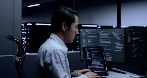 Close Up Of Asian Male Programmer With A Tablet Writing Code By Desktops In The Server Room