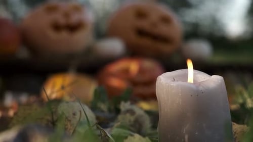 Brennende Kerze, Nahaufnahme auf verschwommenem Halloween-Kürbiskopf, Hintergrund, Kürbis mit geschnitztem Gruselmotiv
