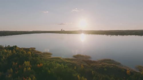 The drone shot captures a lake and its shoreline as the drone moves forward. In the background, the