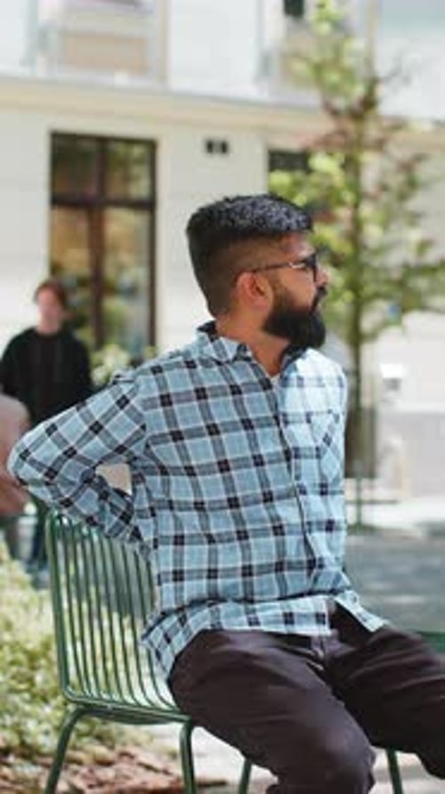 Man Seated on Chair Experiencing Back Pain