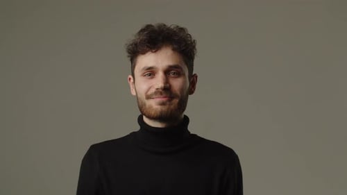A Smiling Man in a Black Sweatshirt Looks Directly Into the Camera Studio Video of a Guy with Curly