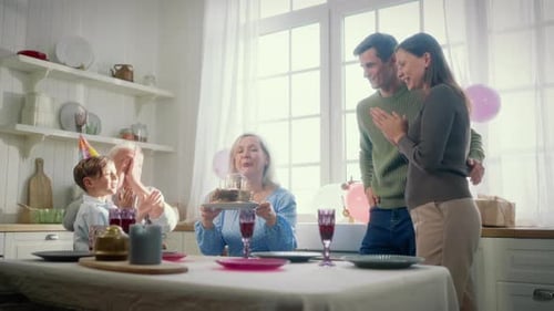 Family Celebrates Birthday with Cake and Candles in Kitchen