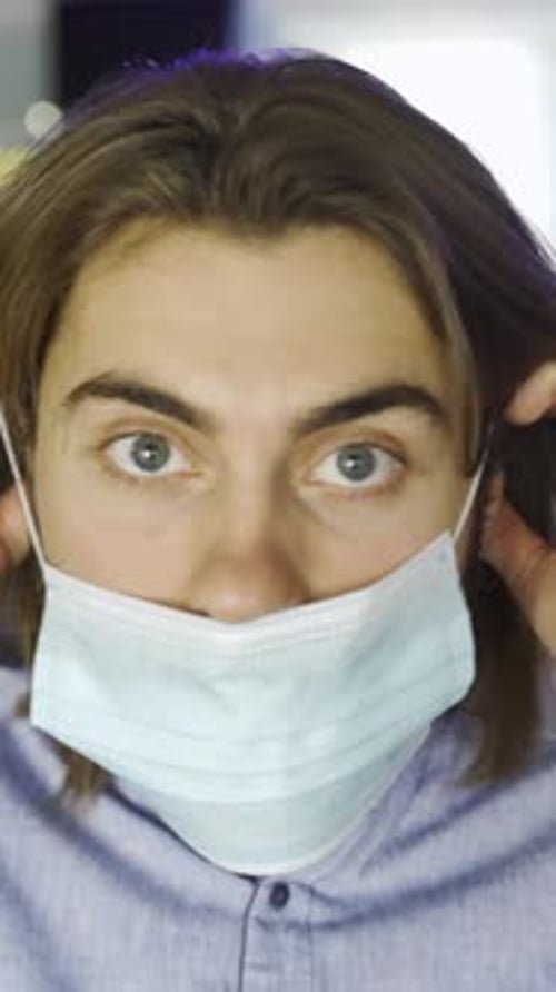 Close Up of a Bearded Caucasian Man Putting on a Blue Medical Face Mask During Coronavirus
