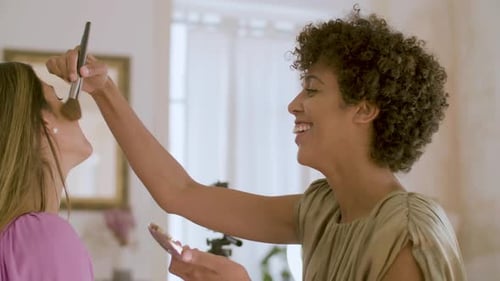 Side View of Young Black Woman Applying Powder on Friends Face