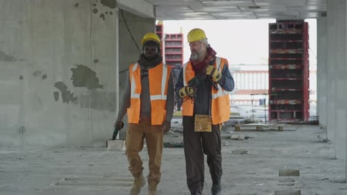 Construction Workers Holding Drills Walking on Building Site