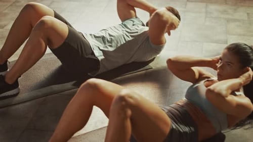 Athletic people doing sit-ups in gym
