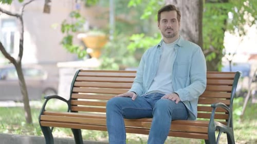 Man Sitting on Park Bench in Urban Environment