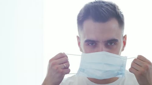 Man Puts On a Disposable Surgical Mask