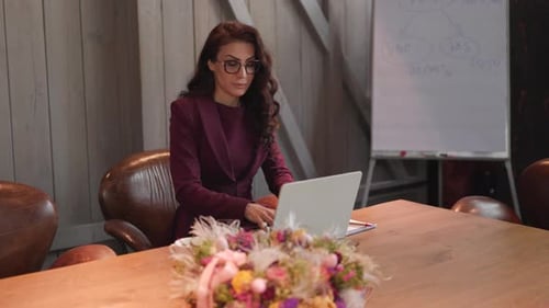 A Professional Businesswoman is Currently Engaged in Work on a Laptop in a Modern Office Setting