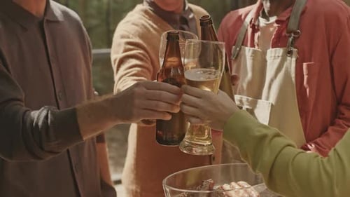 Companhia de amigos brindando com cerveja em uma festa de churrasco na natureza