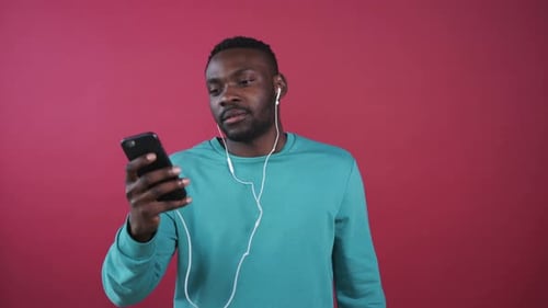 Man Listens Using Wired Headphones and Smartphone