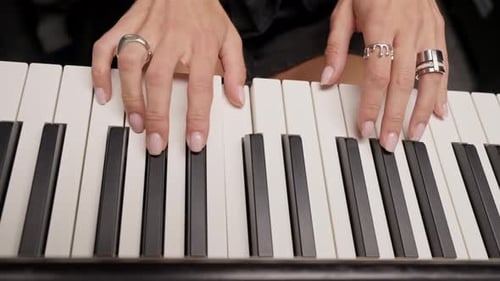 Close-up of a woman's hands in silver rings playing beautiful lyrical melody on the piano keys
