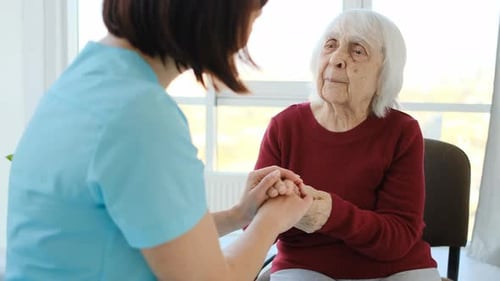 Senior Woman Talking with Medical Worker Holding Hands
