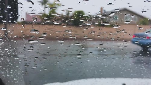 Regentropfen auf der Windschutzscheibe des Autos während der Fahrt, Nahaufnahme.