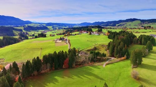 Aerial view shows a large expanse of green fields, dotted with trees and a few houses.