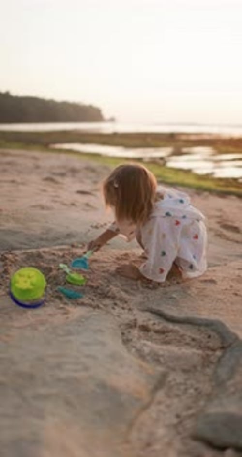 Little Child Girl Playing with Sand on Ocean Beach with Sunset Tones