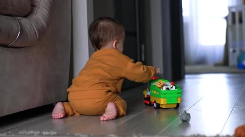 Barefoot Infant Playing With Toy Truck Indoors
