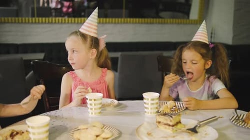Children Have Fun Eating Birthday Cake in Festive Caps Talking and Laughing in a Cozy Festive