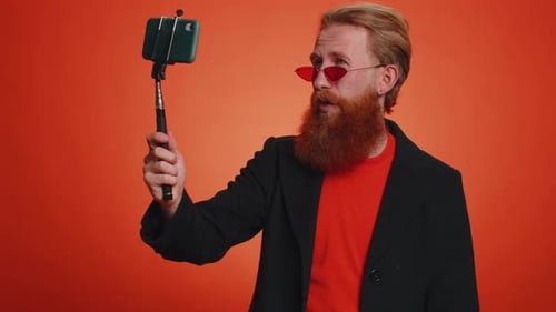Stylish Adult Speaking Using Smartphone Selfie Stick